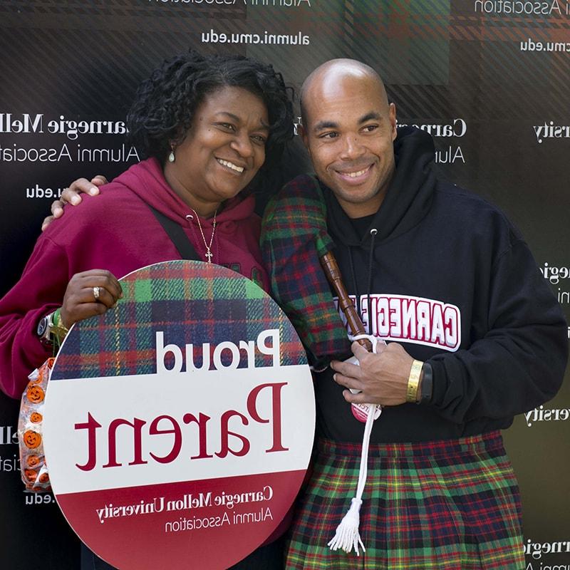 Photo of a student and his mother, holding a sign that reads 